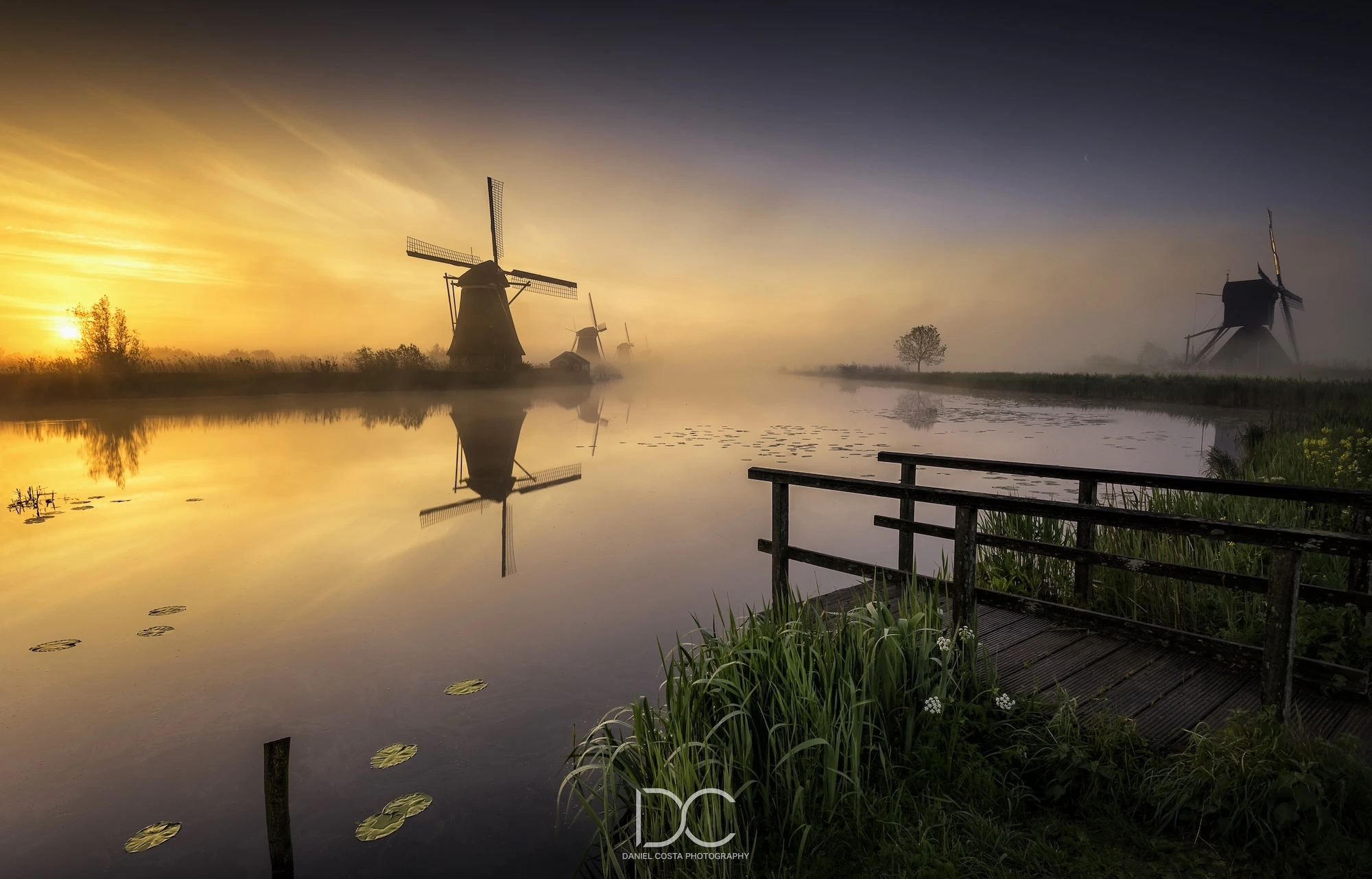 Foggy nature with windmill by the water